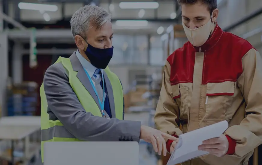 Factory manager and worker reviewing production tracking documents on the shop floor at inevia